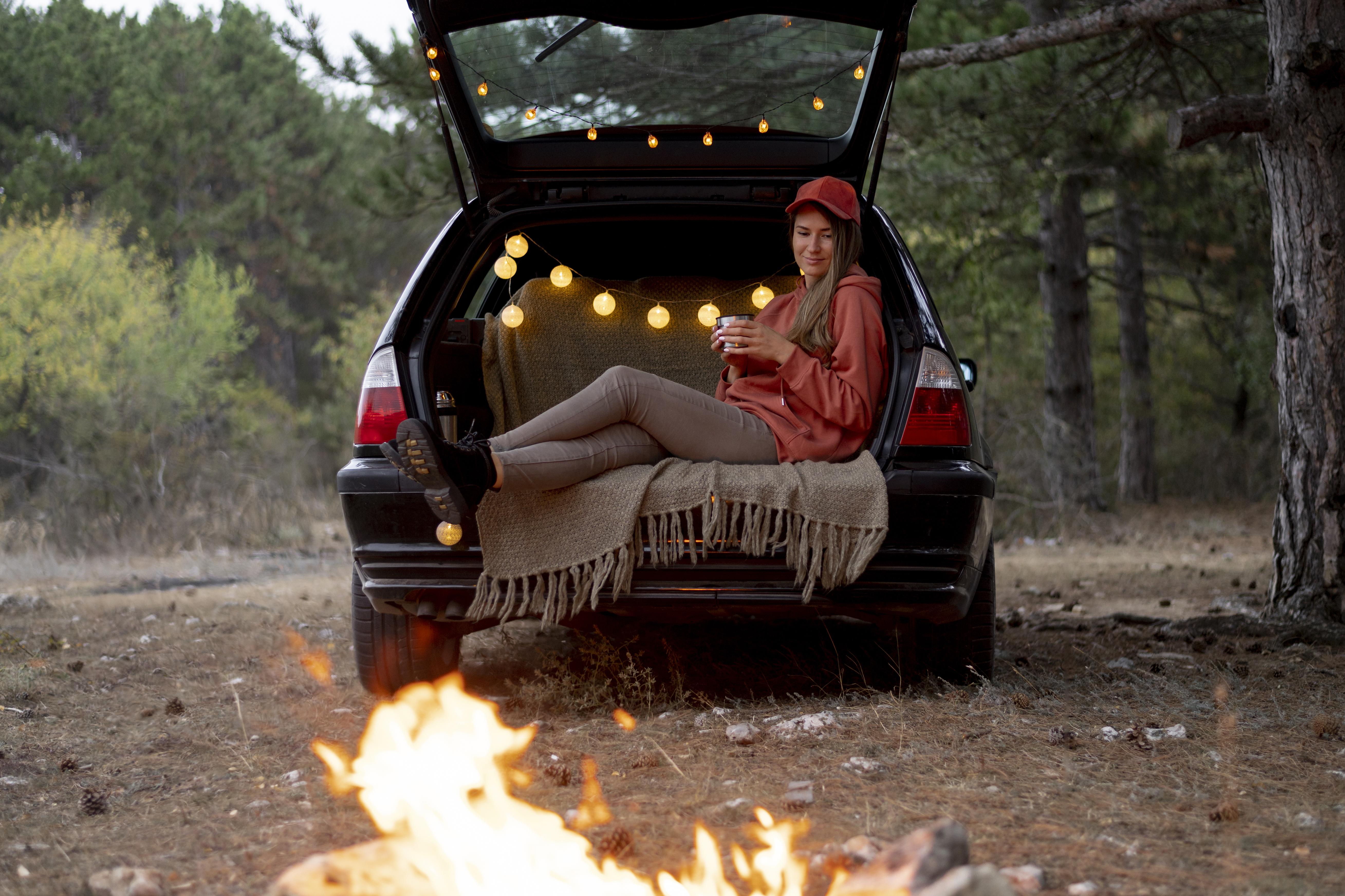 Woman sitting in the back of her car camp setup